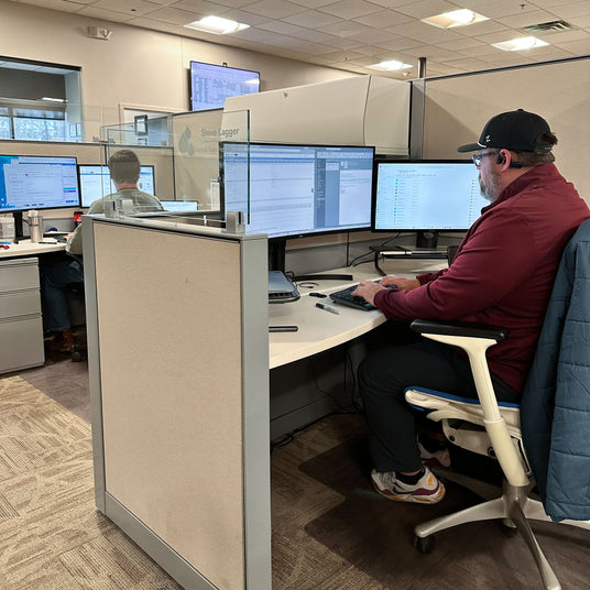 Person sitting at a desk with multiple computer monitors in an office setting
