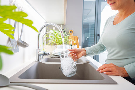 woman filling a water pitcher with tap water at the sink